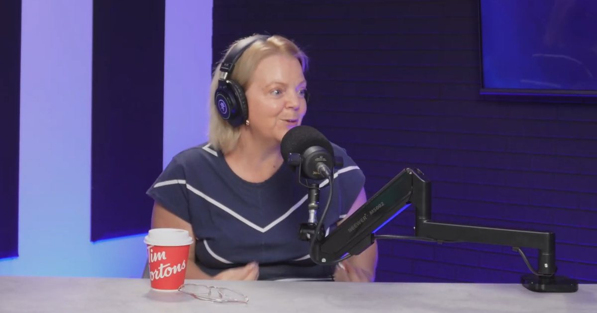 Anick Lapratte au micro du studio Pod'Excuse, souriante, un café Tim Hortons posé sur la table